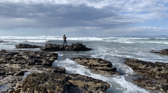 ocean waves on rocky shore with Sam on rocks