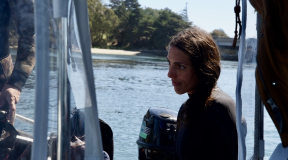 Kat Behesgti on research vessel, water and shoreline in background